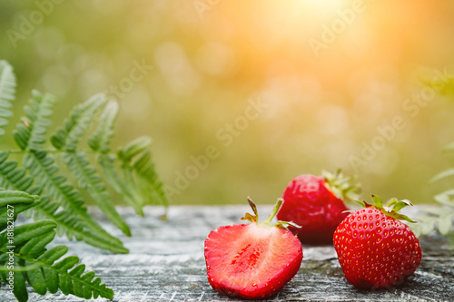 Strawberries on a wooden gray table on a green background, leaves of paparatnik, strawberry season. сopy space for text, photo