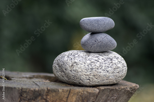 Three zen stones pile on wooden stump  white and grey meditation pebbles tower