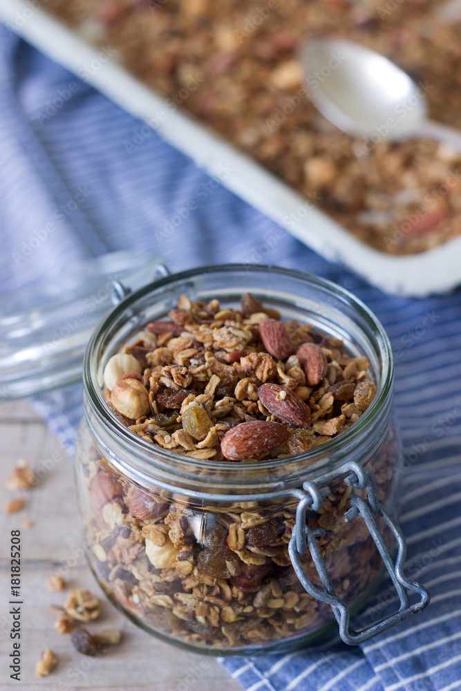 Homemade granola in a glass jar and on a baking sheet. Rustic style. Homemade granola in a glass jar and on a baking sheet. Rustic style.