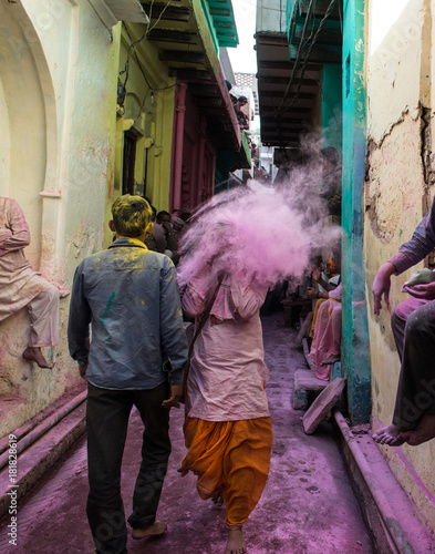 People sitting on the street in the villages of Barsa and Mathura India during the holi festivals days and are covered with powder in all different colors especially pink and red photo