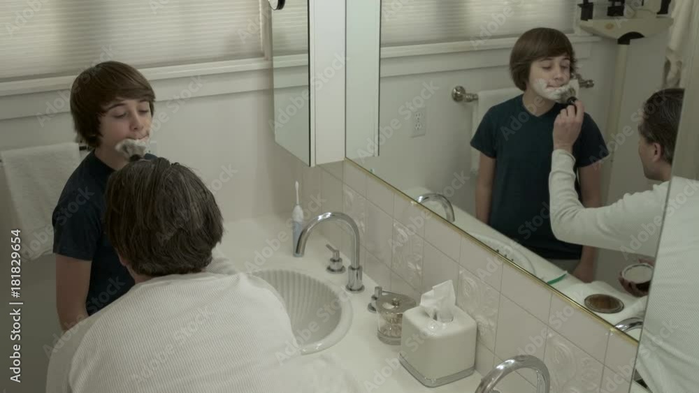 Father smearing shaving foam on face of his son and his own Father smearing shaving foam on face of his son and his own