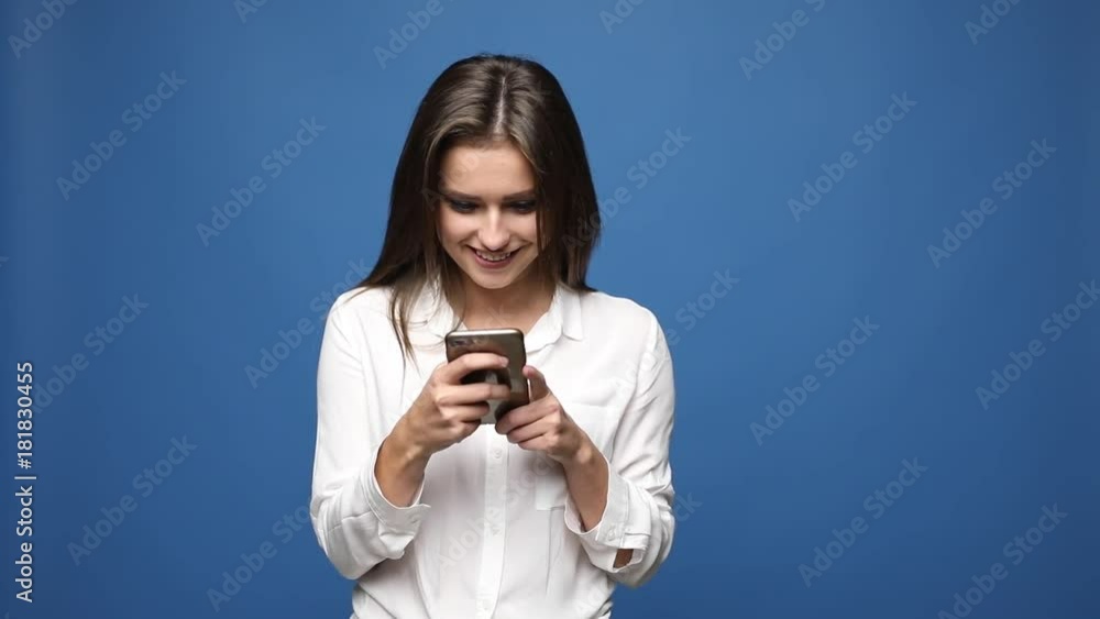 Happy satisfied young girl texting message on mobile phone happy isolated over blue Happy satisfied young girl texting message on mobile phone happy isolated over blue
