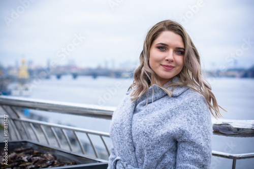 A woman of plus size, American or European appearance walks in the city enjoying life. A young lady with excess weight, stylishly dressed in coat at the center of the city. Natural beauty