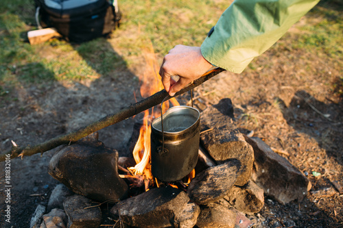 Female hand holding cast iron pot on a campfire. Cooking at the campfire