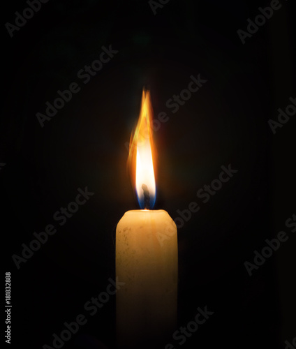 Single lit candle with flame on black.