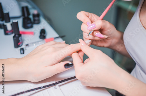 Manicurist hand painting client s nails. Professional workplace