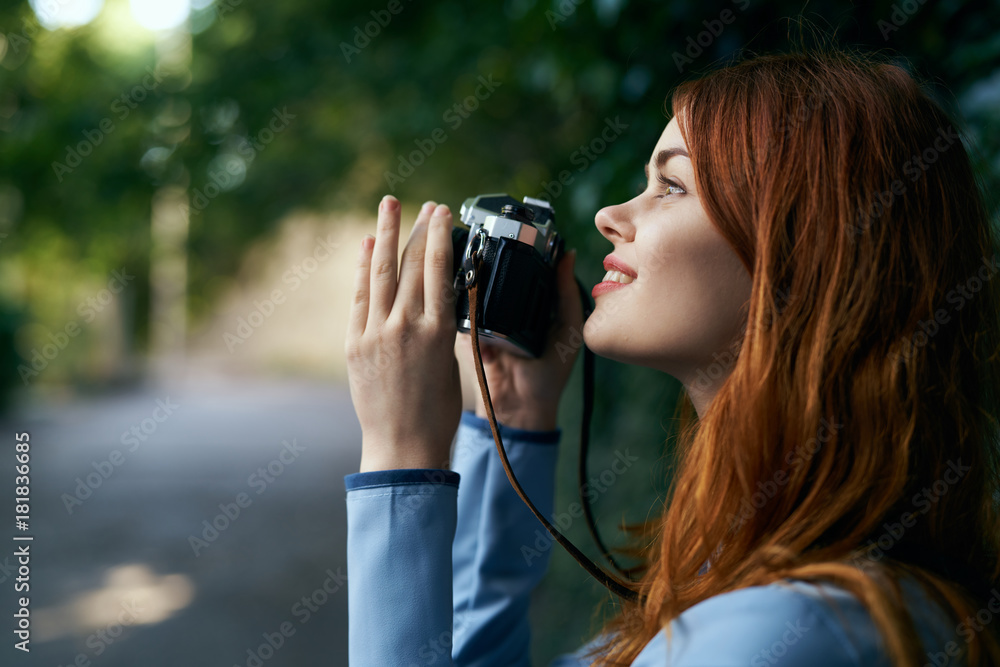Beautiful young woman taking pictures at the camera on the street