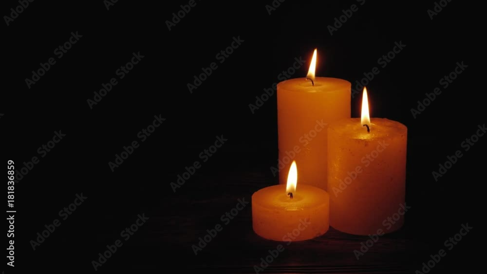 Warm candles gently burning in a black void. Candles group together on dark background Warm candles gently burning in a black void. Candles group together on dark background