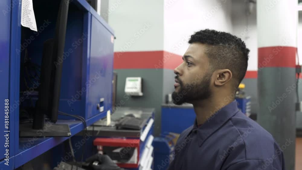 Push-out shot of a mechanic using a computer Push-out shot of a mechanic using a computer