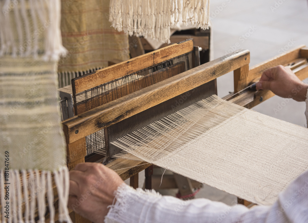 Hands of a man weaving on a loom