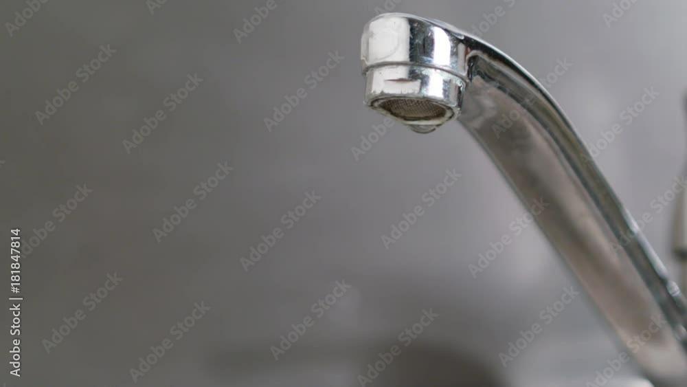 Water dripping from a tap into a sink. Close-up shot Water dripping from a tap into a sink. Close-up shot