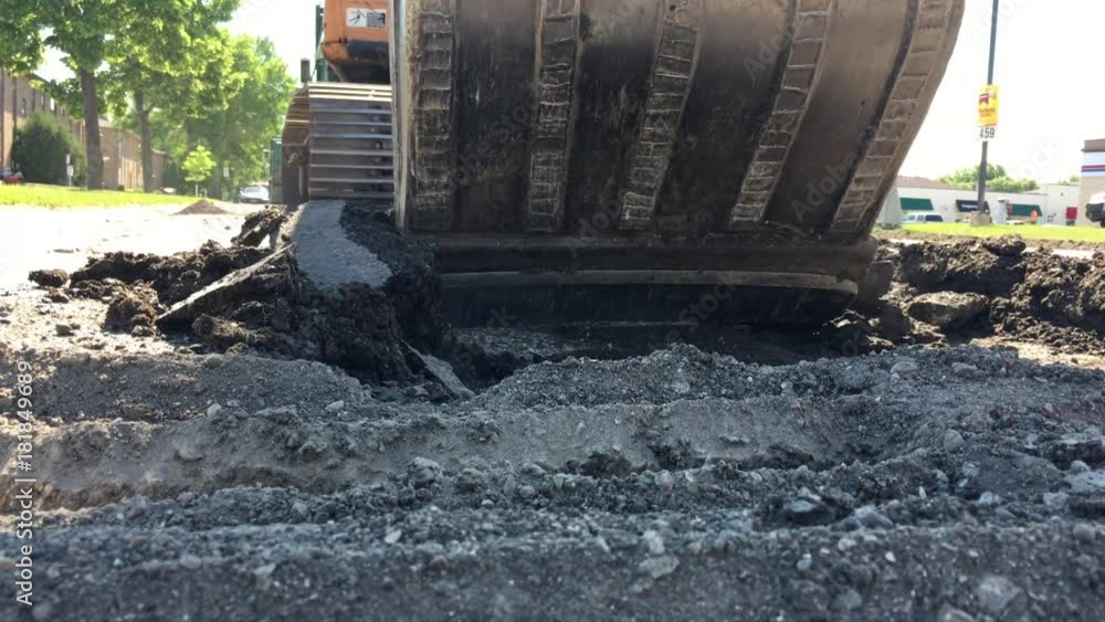Backhoe tearing up road with bucket approaching camera and then pulling back section of broken concrete. Backhoe tearing up road with bucket approaching camera and then pulling back section of broken concrete.