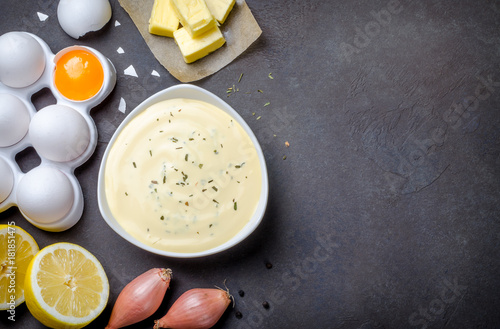 Basic french sauce bearnaise in a white bowl with ingredients, b
