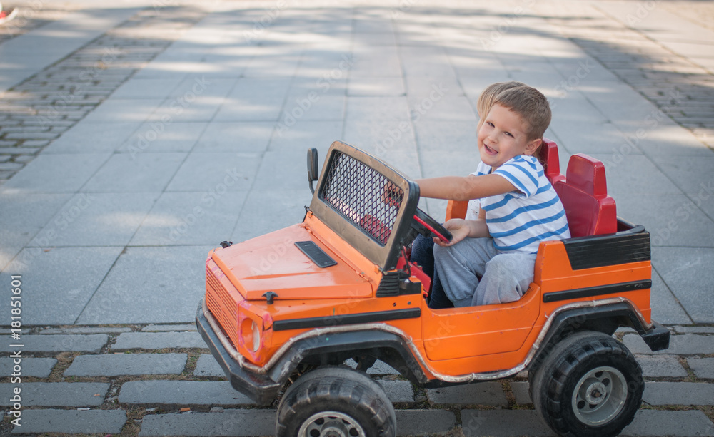 Little brother drives his sister in car toy Little brother drives his sister in car toy