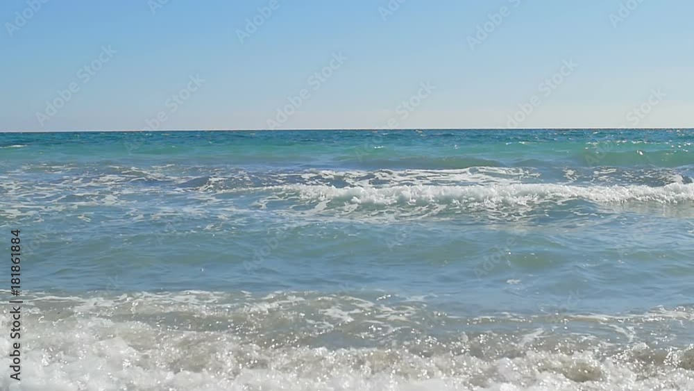Waves landing on coast. Clear blue water. Slow motion