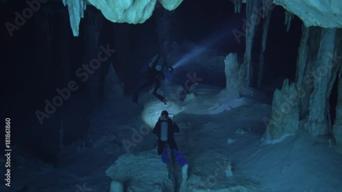 cenote with beautiful blue water, divers swiming through stalagmit cave, cenote dos ojos