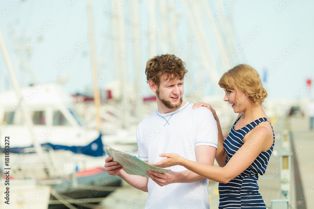 Tourist couple in marina looking up directions on map