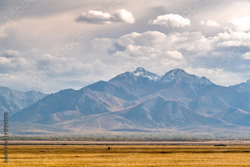 Horseman galloping across the Mongolian steppe on a background of mountains