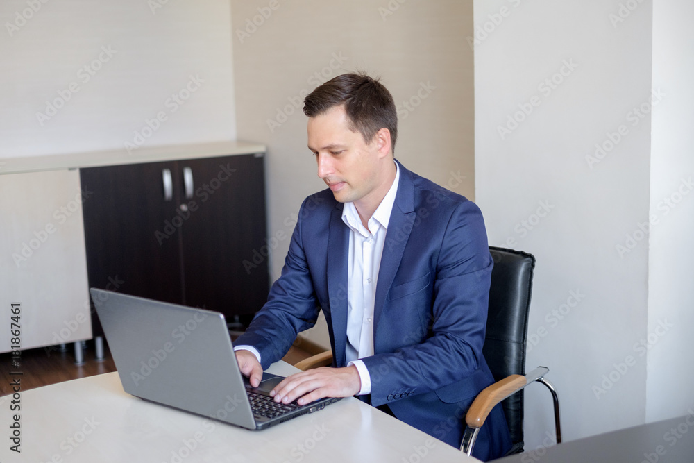 Young man working in office, sitting at desk, looking at laptop computer screen. Young man working in office, sitting at desk, looking at laptop computer screen.