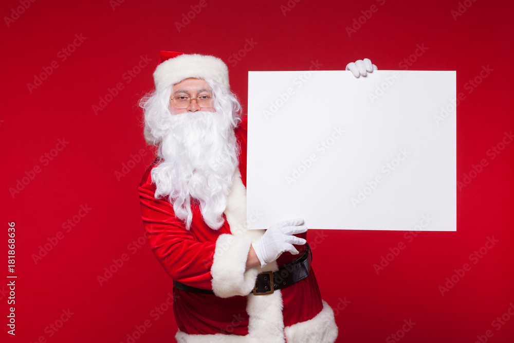 Santa Claus pointing in blank advertisement banner isolated on red background with copy space Santa Claus pointing in blank advertisement banner isolated on red background with copy space