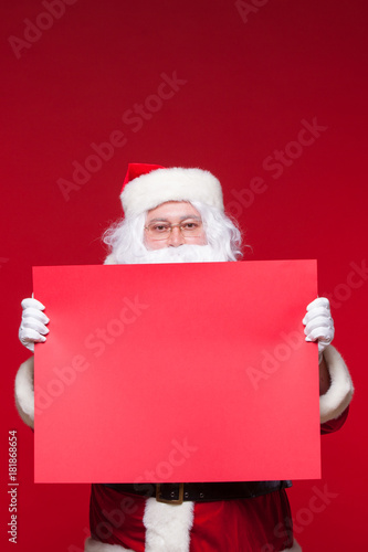 Santa Claus pointing in blank advertisement banner isolated on red background with copy space red leaf