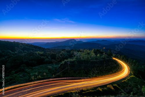 Sunrise scence of car light trail to the top with curve of road at Doi Inthanon National park in Chiang Mai Province, Thailand.