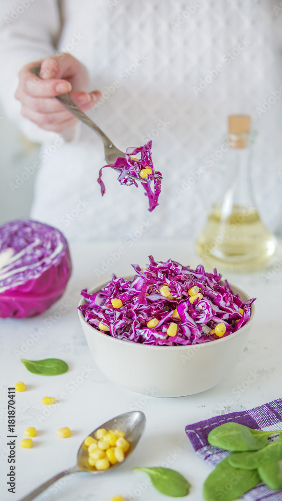 Salad of red cabbage and corn. Woman's hand holds fork with salad