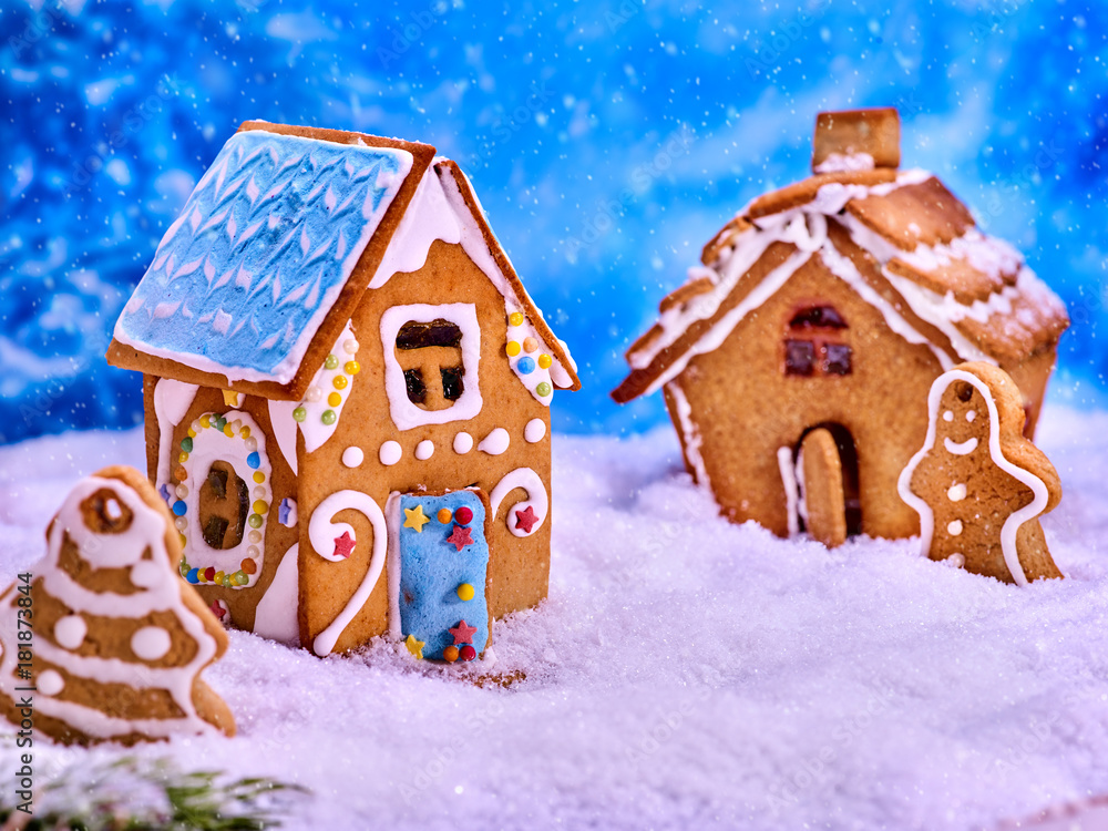 Christmas cookies gingerbread houses and gingerbread man next to them in the snow. Village Xmas sweet food in winter background.