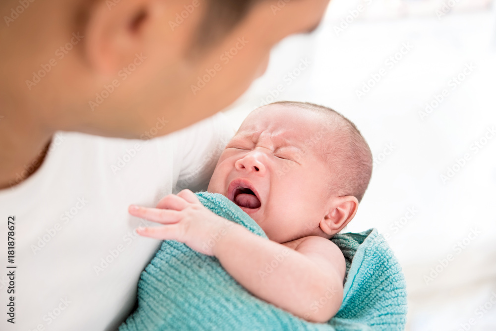 Young father holding crying sleepy cute little newborn baby