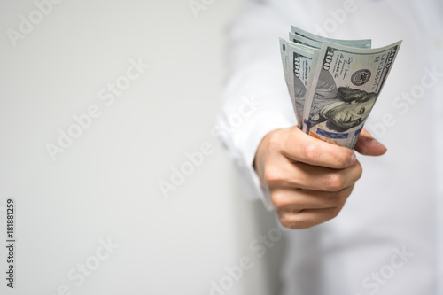 Very happy businessman hand holding and grabbing US dollar (USD) money bills in hand and passing to client in concept of investment, success and profitable business.