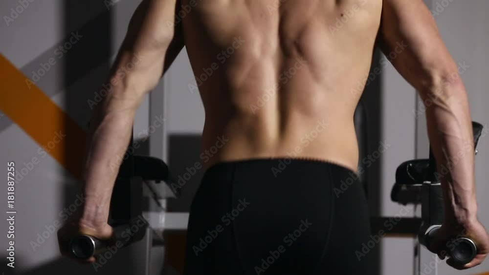 Strong powerful male exercises for pectoral muscles and triceps with dips. Close-up, relief of the body. Strong powerful male exercises for pectoral muscles and triceps with dips. Close-up, relief of the body.