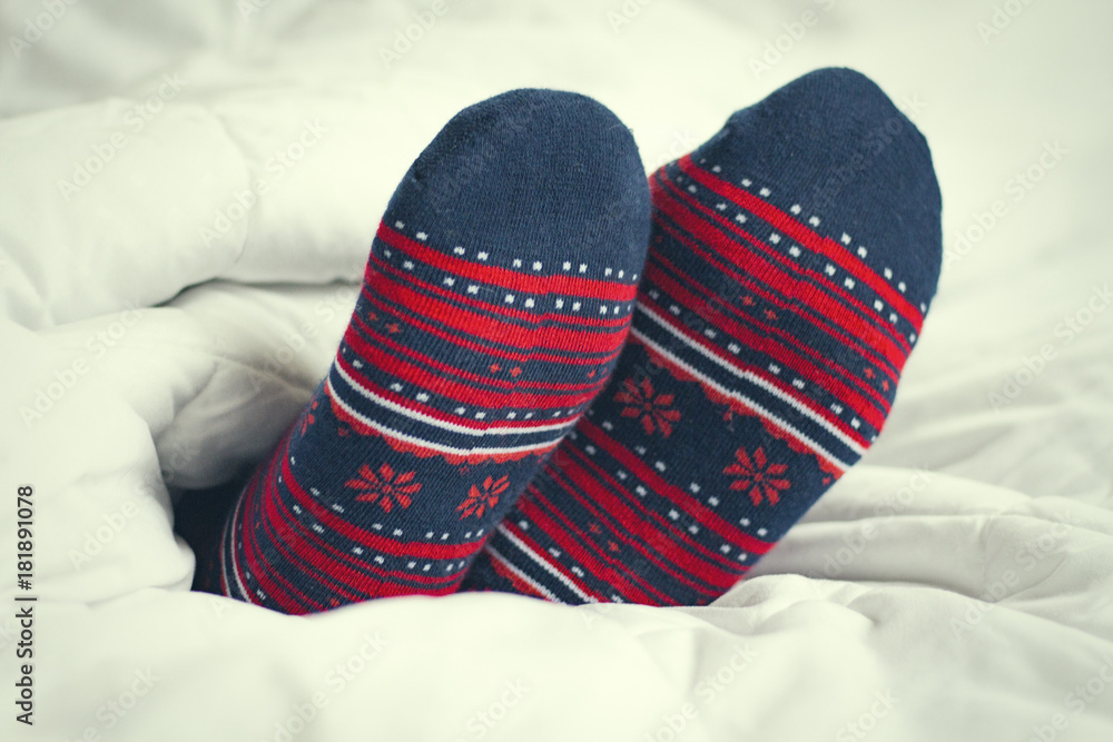 Female feet in socks with ornament on a white blanket background