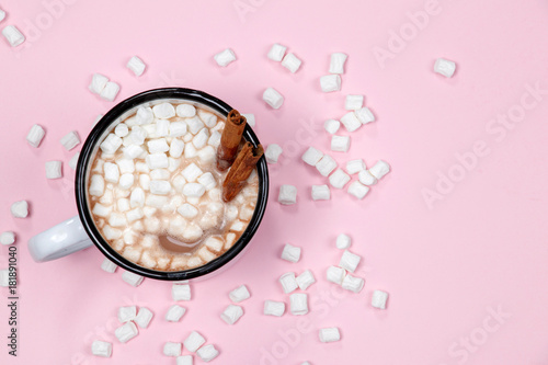 White cup of hot chocolate drink with marshmallows and cinnamon on pink background. Winter time. Christmas holiday concept. Flat lay. Top view.
