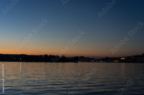 sunset on lake lucerne viewed from boat with city background