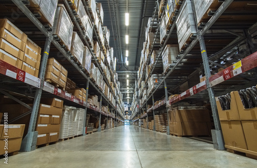 Large warehouse logistic or distribution center. Interior of warehouse with rows of shelves with big boxes