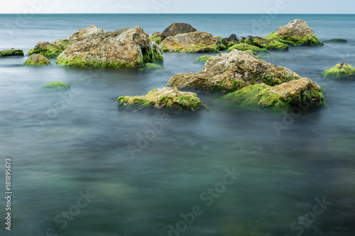 long exposure of sea and rocks covered with green algae