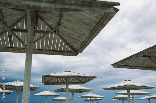 Wooden parasols and empty deckchairs on deserted beach on the off-season cloudy day