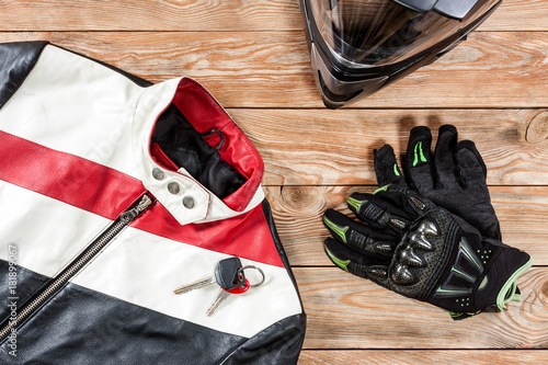 View of motorcycle rider accessories placed on rustic wooden table.