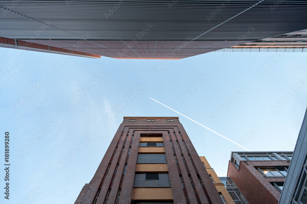Brick Tower and Building Complex under a blue Sky, with a Jet Trail across Brick Tower and Building Complex under a blue Sky, with a Jet Trail across
