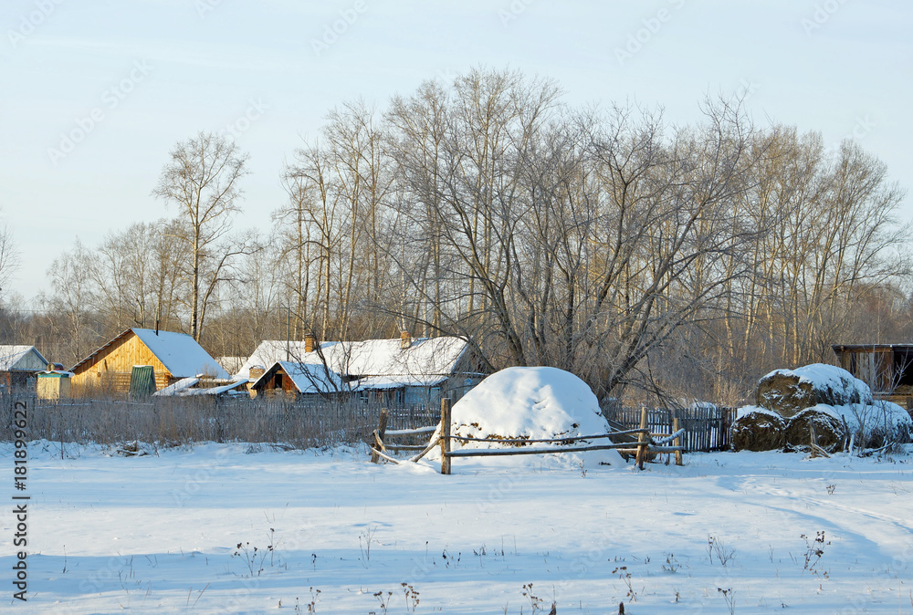 Countryside in winter. Rural scene with a haystack at the edge of village Countryside in winter. Rural scene with a haystack at the edge of village