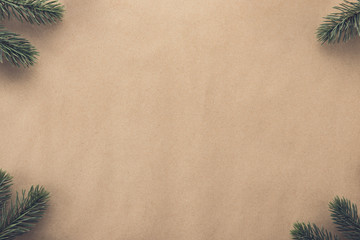 Christmas background border design with green pine at corners on brown paper