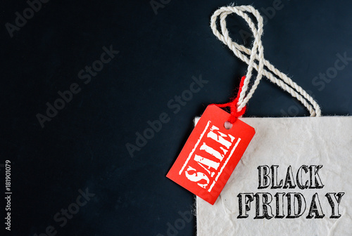 Shopping bags with red sale tag on black background. Black Friday concept.