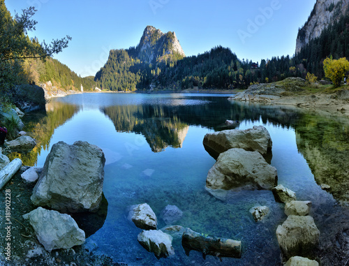Idyllic autumn scene in the Alps with mountain lake reflection.