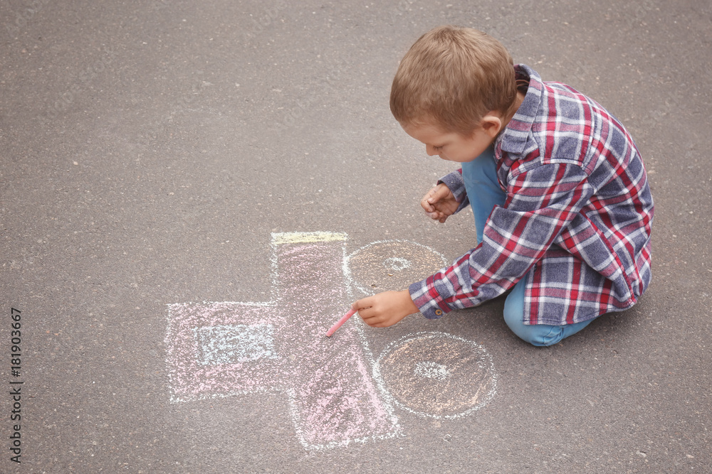 Naklejka premium Little boy drawing car with chalk on asphalt