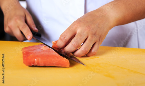 Chef slicing salmon with knife in professional kitchen