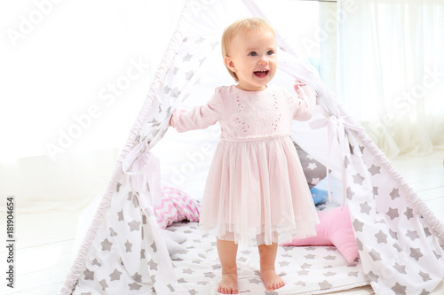 Cute baby standing in tent ...