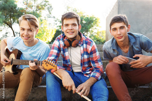 Teenager musicians sitting on steps outdoors © Africa Studio