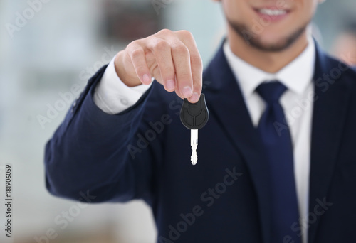 Car salesman holding key on blurred background
