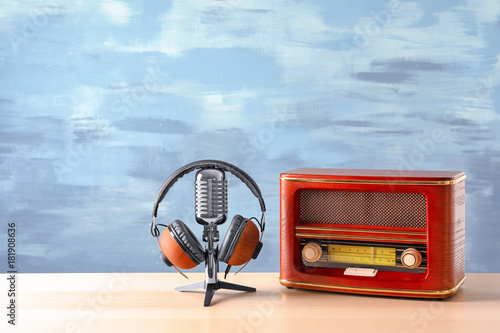 Retro radio, microphone and headphones on table against blue wall photo