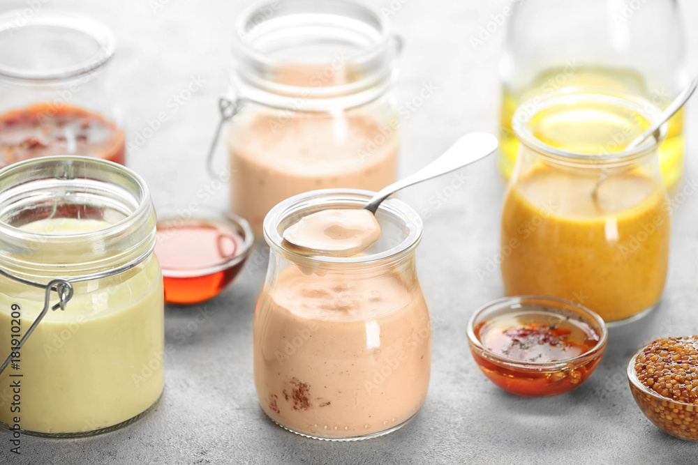 Jars with tasty sauces for salad on table Jars with tasty sauces for salad on table